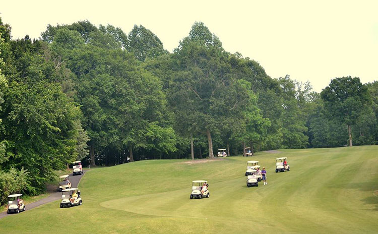 golf carts riding down the side of the fairway